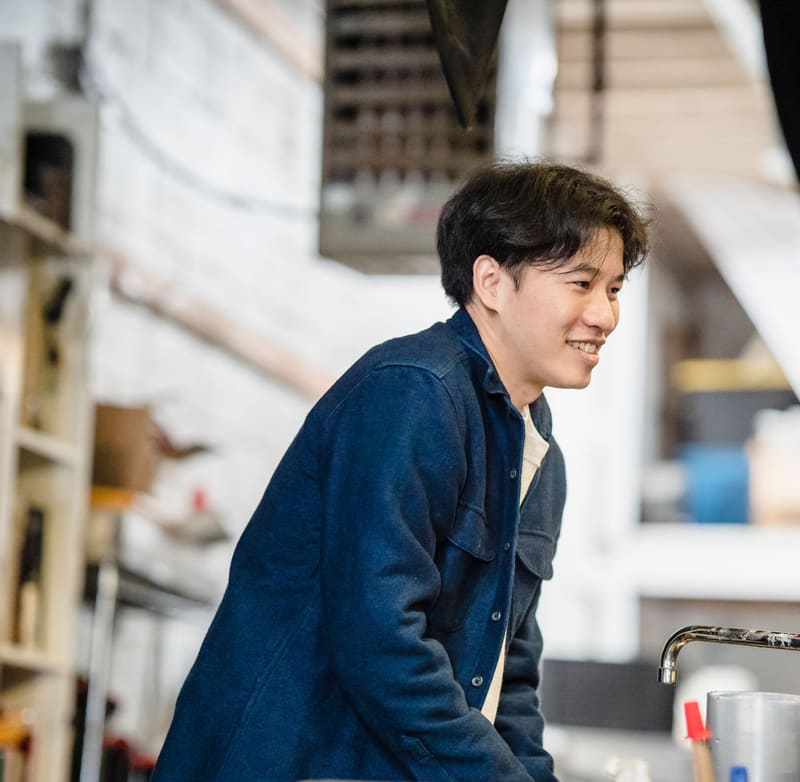 Smiling young worker at a stainless steel utility sink with a gooseneck faucet
