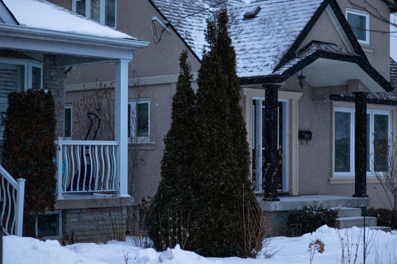 Snowy residential street of houses with porches in Toronto