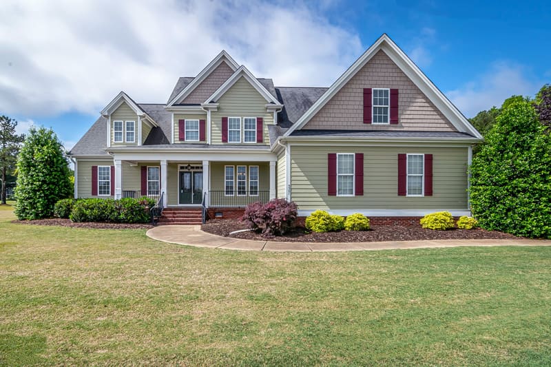 Two-story suburban house with a front porch and a manicured lawn