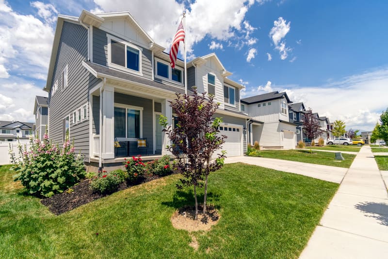 Suburban street of two-story houses with lawns and an American flag
